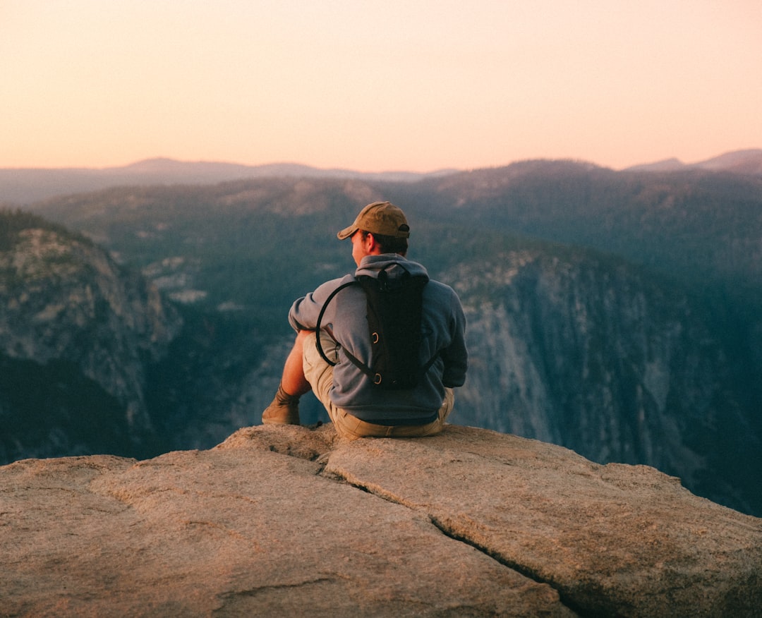 man-in-black-t-shirt-and-brown-hat-sitting-on-rock-44q19jsipxi